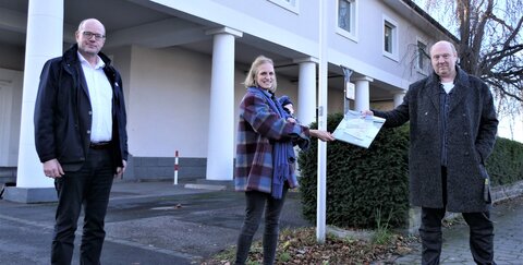 Freude über großzügige Spende: v.l. Kulturdezernent Horst Wende, Antonia Lecour mit Sohn Lando und Frank Baquet vor der Wand, an der die LED-Tafel befestigt wird.